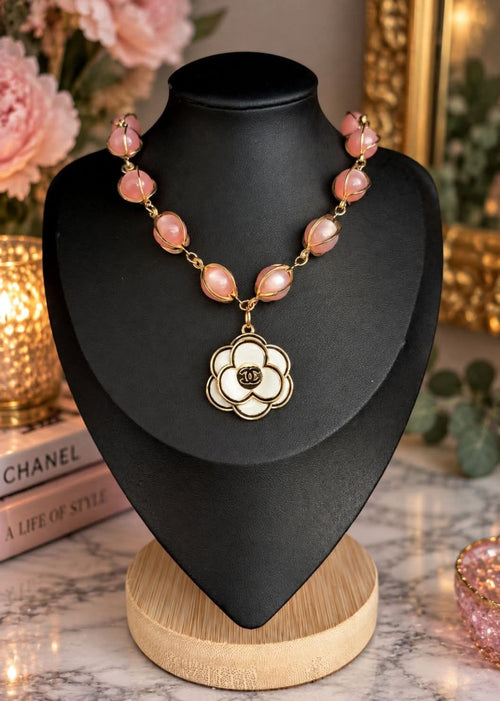 Blush pink pearl-style bead necklace with gold-tone detailing and white floral CC pendant