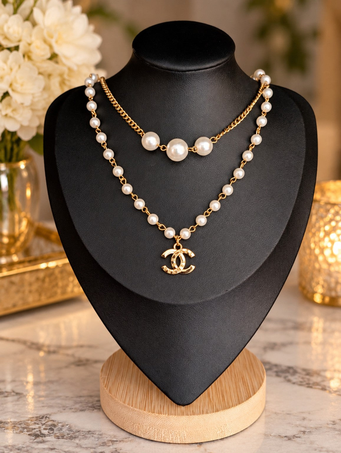 Reworked vintage pearl necklace with gold-tone links and a repurposed CC charm on a black display bust